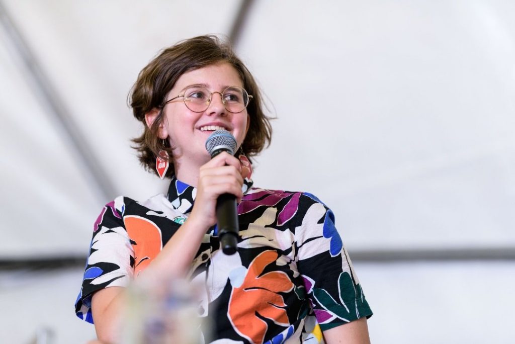 Young woman in colourful shirt talking into microphone